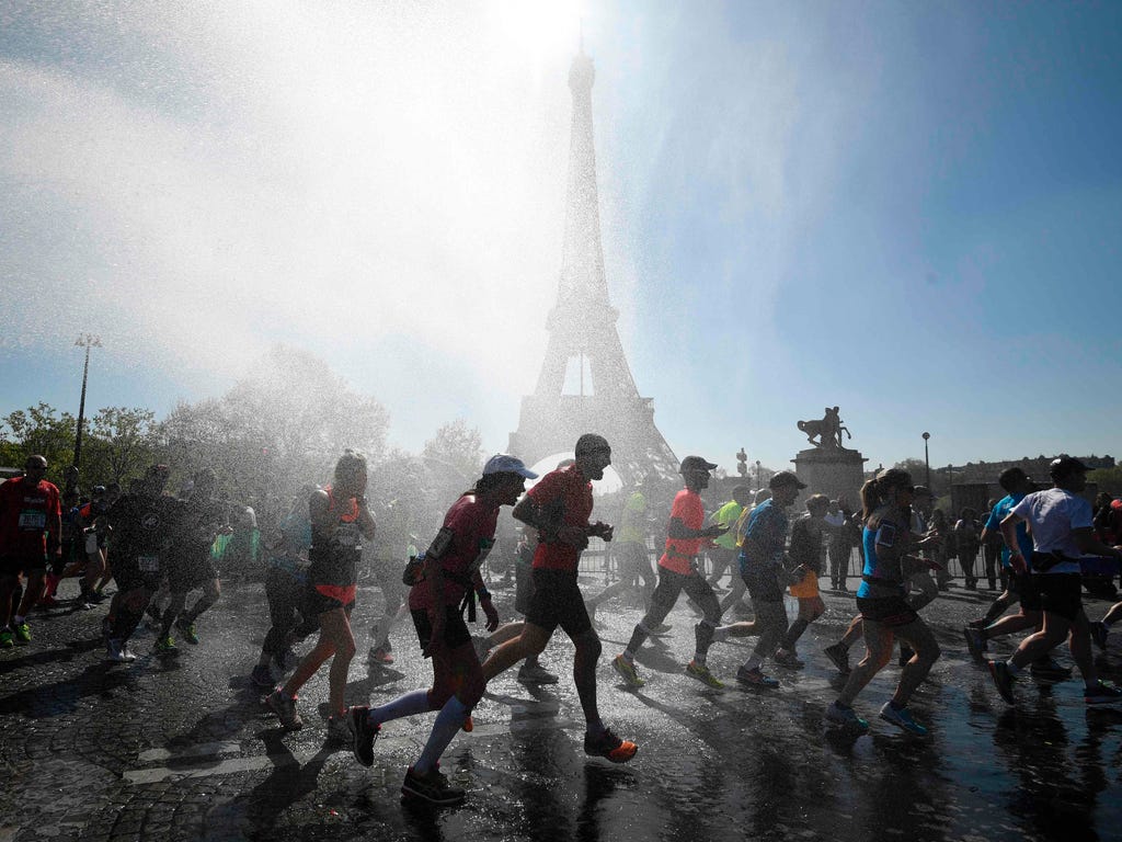 Runners go through a cooling water stream as they compete in the 41st Paris Marathon in front of the Eiffel tower in Paris on April 9, 2017.