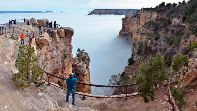 In this photo provided by the National Park Service, visitors to Mather Point on the South Rim of Grand Canyon National Park view a rare weather phenomenon -- a sea of thick clouds filling the canyon just below the rim on Dec. 11, 2014.