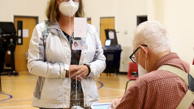 Poll worker Clarence Moreton checks in voter Cindy Voss, Monday, Oct. 19, at the Rye Hill Baptist Church on the first day of early voting in Arkansas.