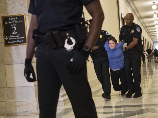 A protestor is arrested outside the office of Sen.