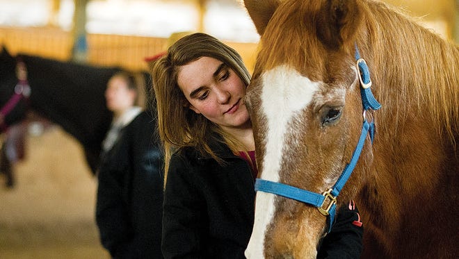 Anistyn Holt, a student at Laramie High School, pets Henry the hose at the Ark Equestrian Center in Laramie, WY. Ark has expanded its equine program to include classes from the Albany County School District.
