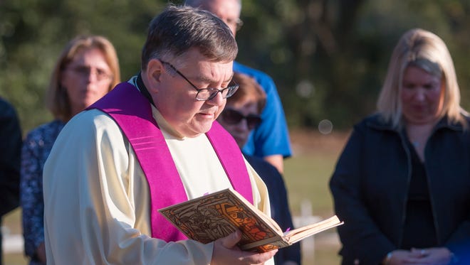 Monsignor James Flaherty leads nearly one hundred friends and teachers of 9-year-old Dericka Lindsay, a student at St. John the Evangelist School, in prayer during a memorial for her at Resthaven Gardens Cemetery in Pensacola on Thursday, November 16, 2017.