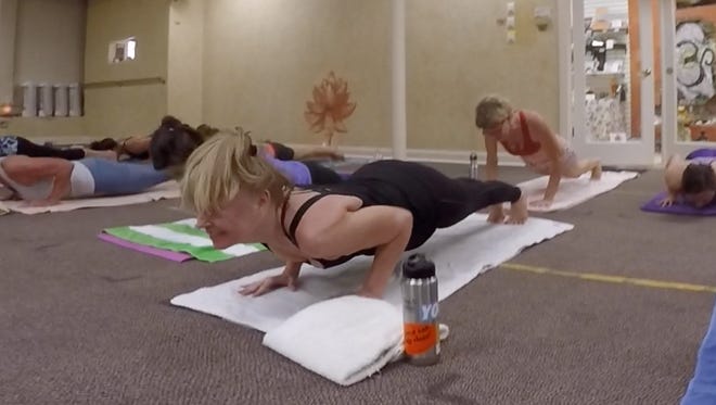 Suzanne Elliott, owner of Bikram Yoga on the Island, hovers in a tricep push-up pose during a recent Inferno Pilates class.