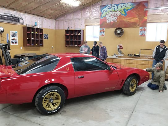 Friends of Obie Nef work on restoring a Pontiac Firebird.