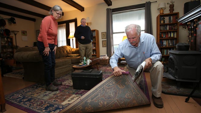 Russ Barnett, right, director of the Kentucky Institute for the Environment and Sustainable Development at the University of Louisville, examines the carpet in the home of Courier-Journal environmental reporter James Bruggers, center, and his wife Christine Bruggers.  He was testing their air quality.Feb. 16, 2017