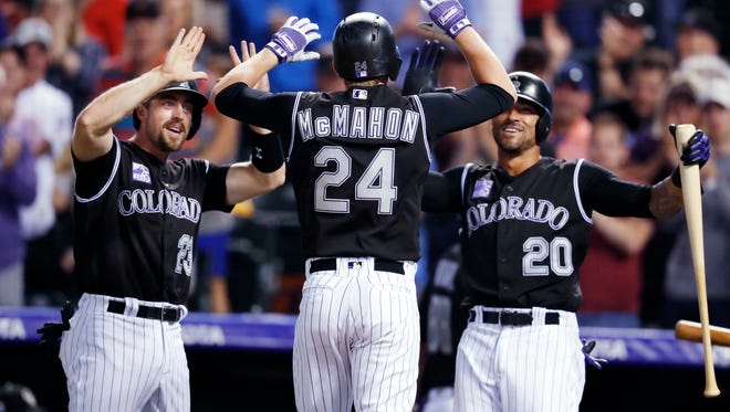 Colorado Rockies pinch-hitter Ryan McMahon, center, is congratulated by Tom Murphy, left, and Ian Desmond as McMahon crosses home plate after hitting a three-run home run off New York Mets relief pitcher Robert Gsellman Wednesday in Denver.