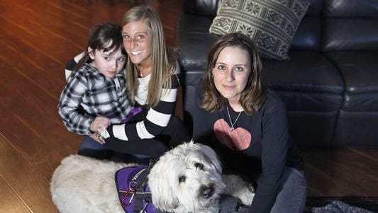 Heather Pereira, right, poses with her daughter, Devyn, left, and Devyn’s nanny, Jenn Horozko, center, with Devyn’s service dog, Hannah.