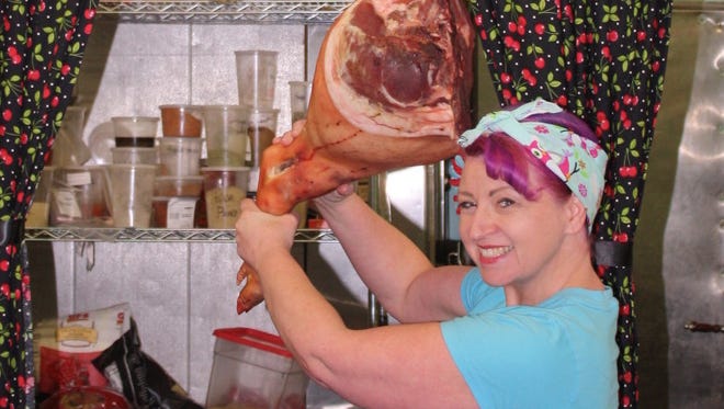 Allison Hines of Butcher Betties prepares to take a swing with a ham on the hoof at her shop in Friendly Market in Florence.