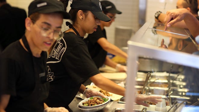 Chipotle restaurant workers fill orders for customers.