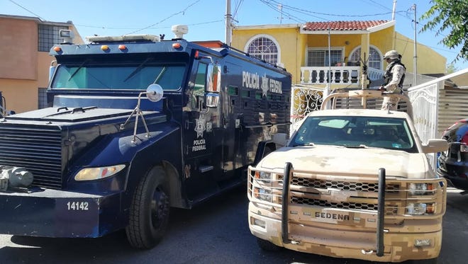 A Mexican Federal Police armored vehicle and army soldier stand outside a raid at a home in Juárez.