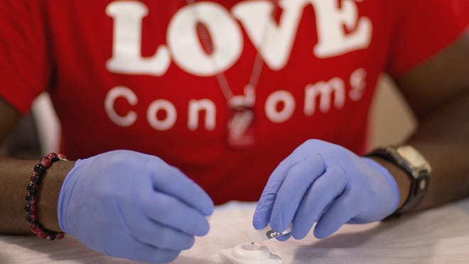 In this June 27, 2013 file photo, Reggie Batiste, program manager with AIDS Healthcare Foundation, administers a free HIV test as part of National HIV Testing Day in Atlanta.