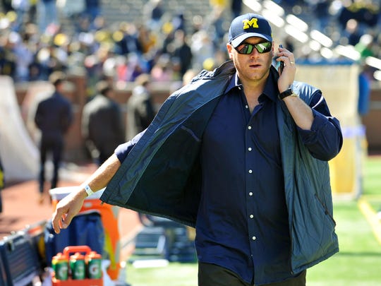 Former Michigan QB Drew Henson talks on a cell phone while walking along the sidelines before the game. Hundreds of former Michigan football players were expected to attend the game.