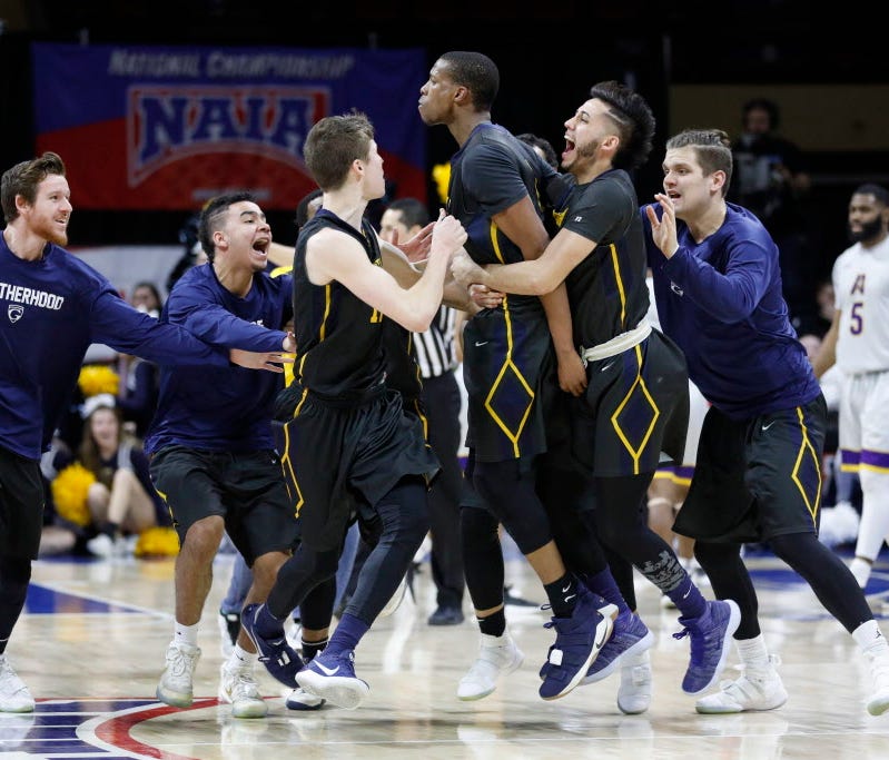 Graceland's Justin Harley, center, celebrates his game-winning overtime basket with teammates.