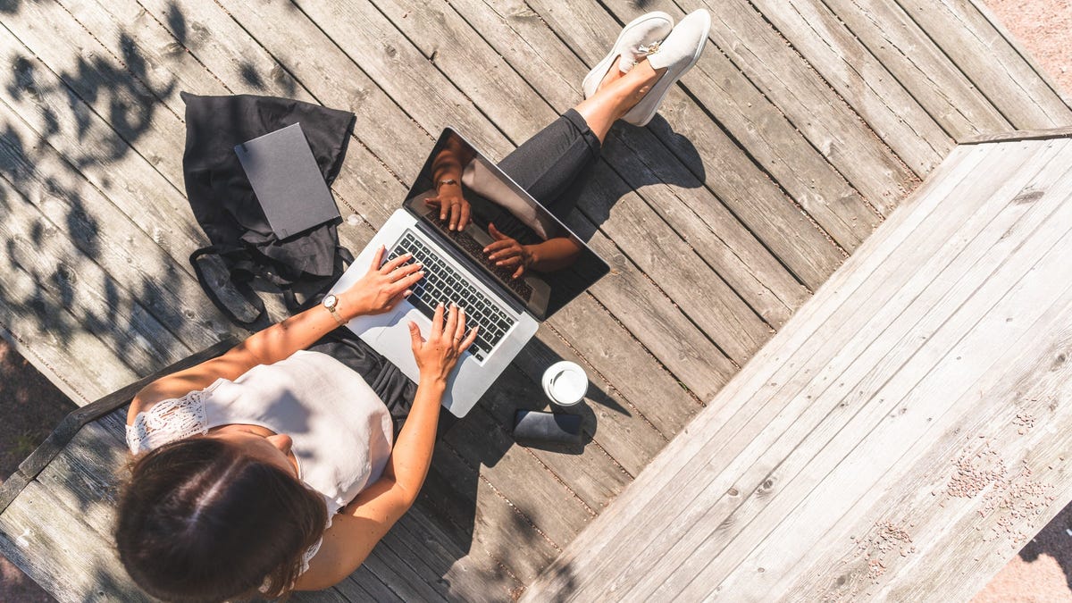 Female gig worker working on her laptop outside.