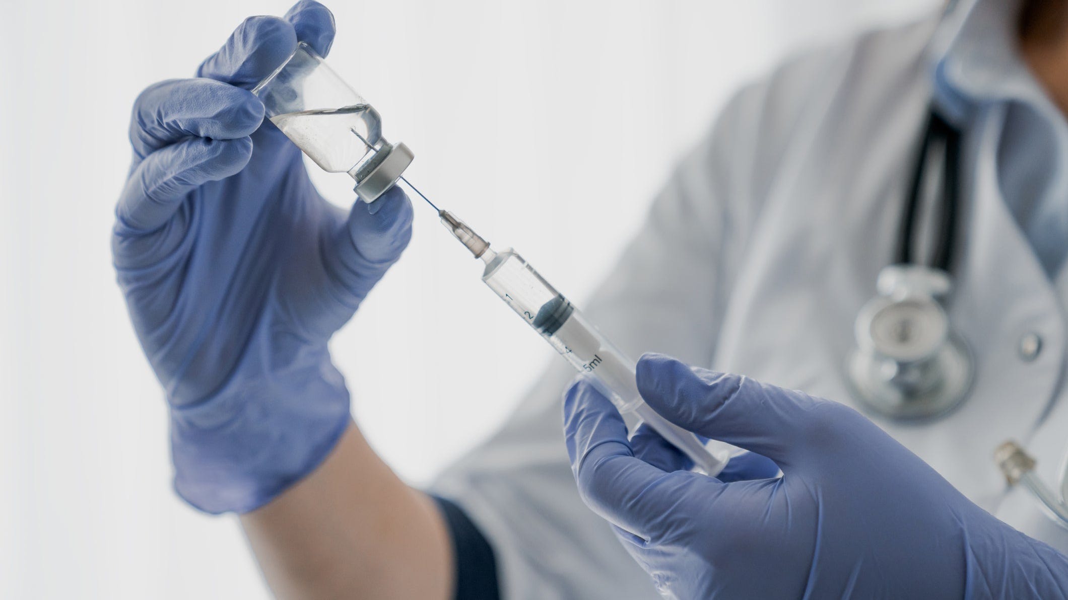 Healthcare worker holding a syringe with needle and a vaccine vial