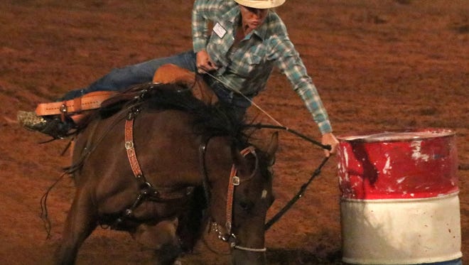 A cowgirl rides her horse around a barrel during the barrel racing event Friday night at the Guy Warden Arena.