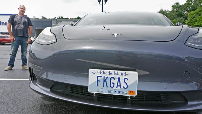 Sean Carroll and his car with his license plate, which says FKGAS. He has an electric Tesla and is in a fight in court about keeping his plate.