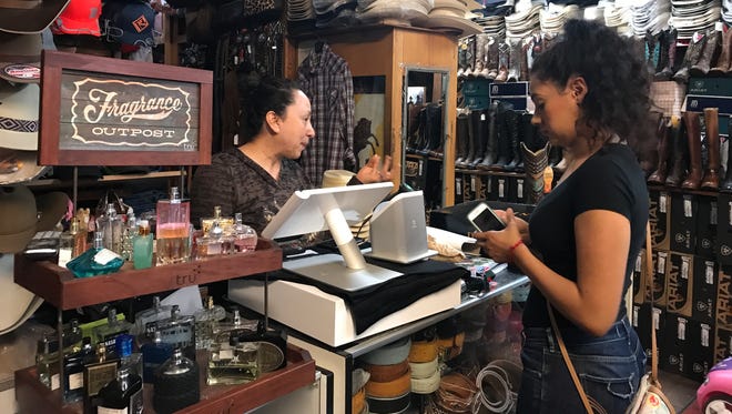 Left, Margarita Servin the owner of El Primo Western Wear in on East Alisal Street rings up a purchase made by to customer Sandra Ramirez