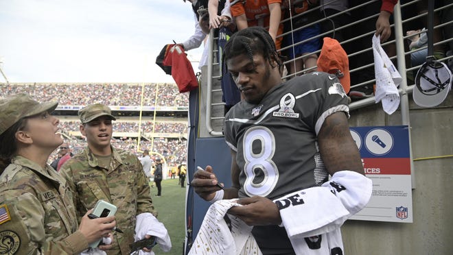 AFC quarterback Lamar Jackson (8), of the Baltimore Ravens, signs autographs for fans at halftime of the NFL Pro Bowl football game against the NFC Sunday, Jan. 26, 2020 in Orlando, Fla.