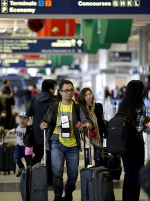 In this Nov. 25, 2015, file photo, passengers walk in Terminal 3 at O'Hare International Airport in Chicago.  An airline trade group said that about 27.3 million people will fly on U.S. airlines over a 12-day period that starts Nov. 18 and ends the Tuesday after Thanksgiving. That's up 2.5% from last year.