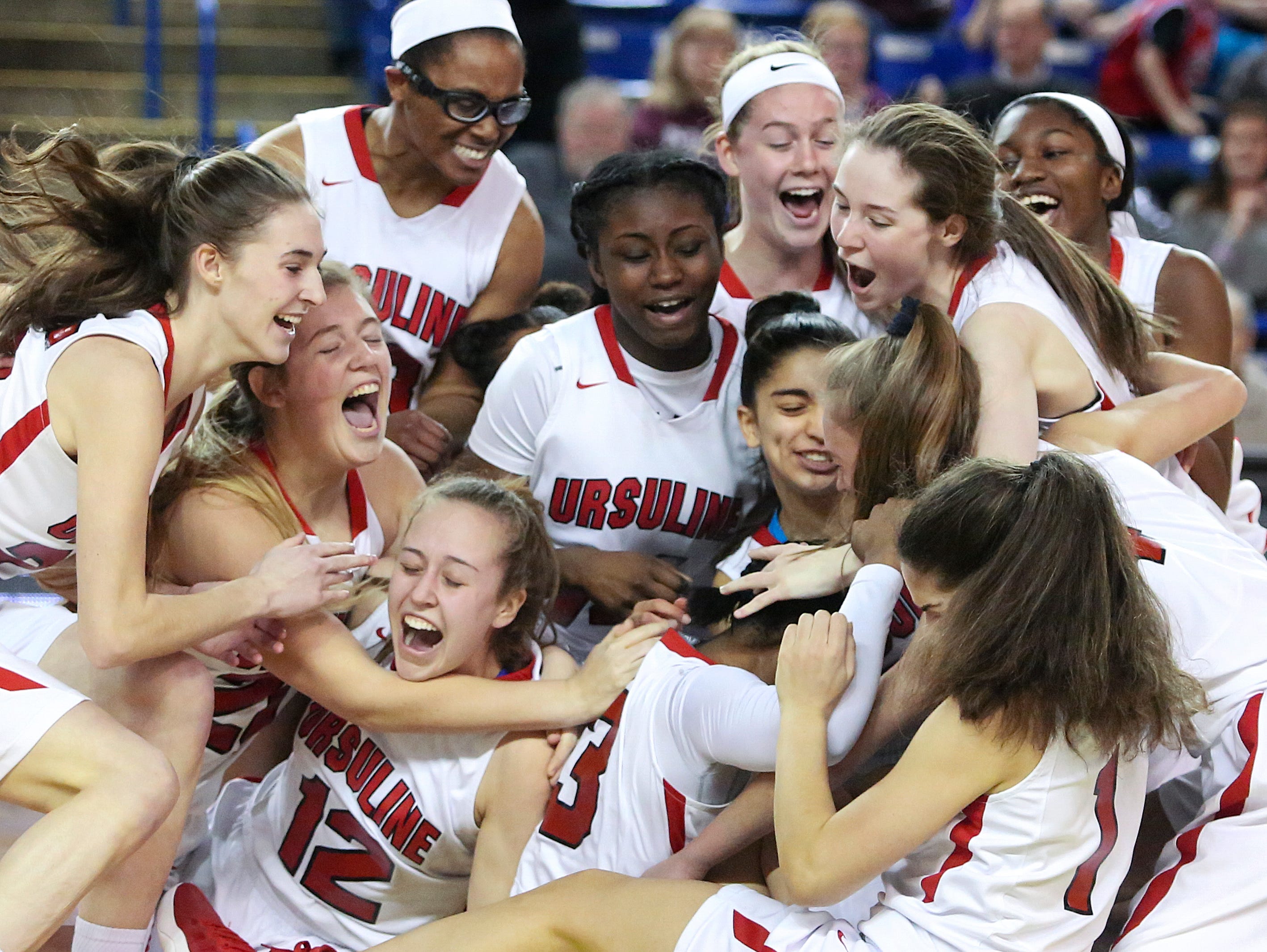 Ursuline collapses in celebration after the Raiders' 54-32 win against Caravel in the DIAA state tournament title game at the Bob Carpenter Center Friday.