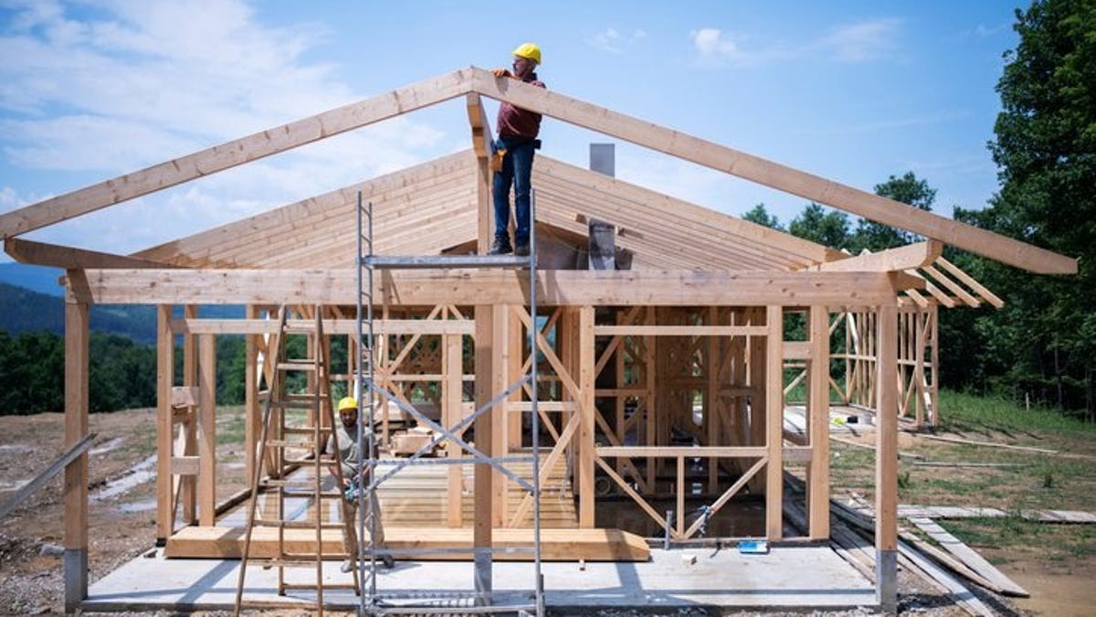 The frame of a house under construction with workers on site.