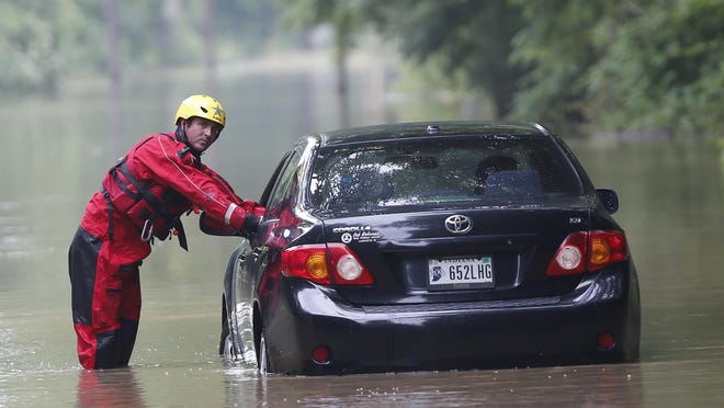 Det. Matt Couch with the Tippecanoe County Sheriff's Office dive team straightens the wheels as a late-model Toyota Corolla is pulled from high water Wednesday, June 17, 2015, on North River Road in West Lafayette. Kartavya Neema, the owner of the car, tried driving through the water when the engine stalled. Couch and a tow truck from Jim's Garage were able to pull the car back to dry pavement. There were no injuries.