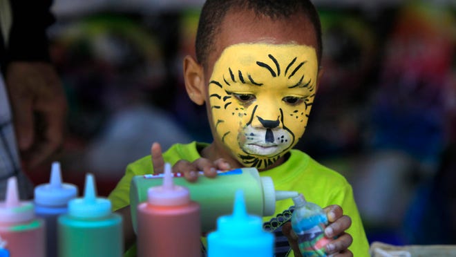 
Kwesi Coley, 4, of Rochester makes sand art after getting his face painted as a tiger at the annual 19th Ward Community Square Fair.
