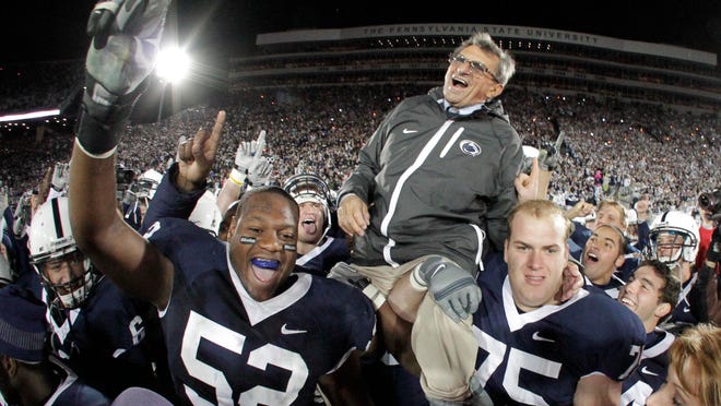 FILE - In this Nov. 6, 2010 file photo, Penn State coach Joe Paterno is carried off the field by his players after getting his 400th collegiate coaching win after their 38-21 victory over Northwestern in an NCAA college football game in State College, Pa. A proposed settlement, announced Friday, Jan. 16, 2015, by the NCAA, will give Penn State back 112 football team wins that were vacated two years ago in the Jerry Sandusky child molestation scandal. If approved, the new agreement also would restore former coach Paterno's status as the winningest coach in major college football history with 409 victories. (AP Photo/Gene J. Puskar, File)
