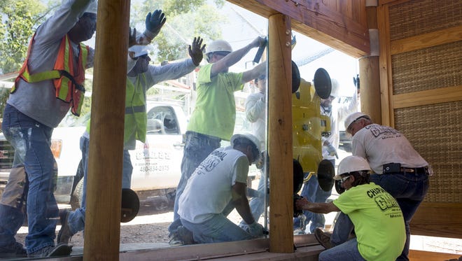 Workers install 850-pound glass windows on visitor viewing area, August 3, 2015, at the new tiger habitat under construction at the Phoenix Zoo.