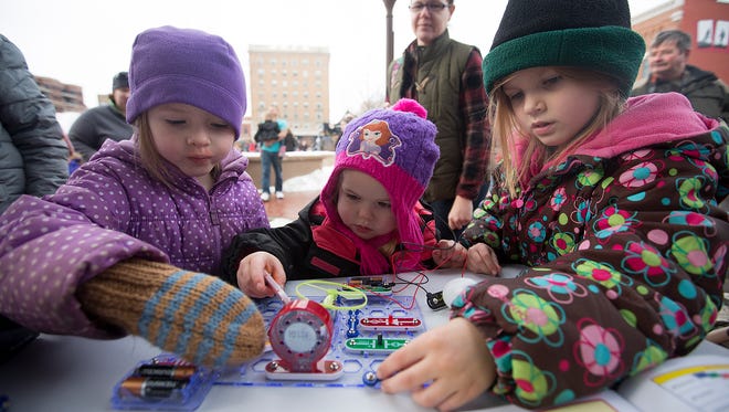 Kira Diestelhorst, 5, of Merrill, left, her sister Liana Diestelhorst, 6, right, and her cousin Madison Diestelhorst, 3, of Edgar, center, play with a circuit outside the Vortex Mobile Lab, which is part of the STEM Scouts program during the fifth annual Winter Fest in downtown Wausau, Saturday, Jan. 30, 2016.