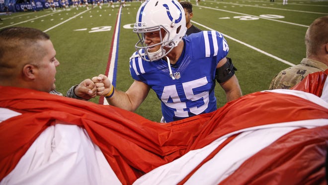 Indianapolis Colts long snapper Matt Overton (45) fist-bumps local military members as they prepare for the national anthem at Lucas Oil Stadium on Oct. 30, 2016.