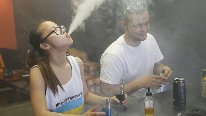Felicity Mason and Derek Hodge puff on their personal vape mods at The Fog Foundry April 2016. The Lafayette City Council considers including e-cigarettes in smoking ordinance.