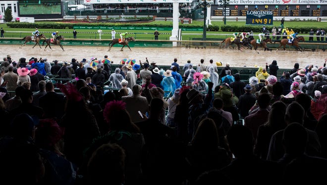 Fans cheer as horses and their jockeys cross the finish line during a race at the 143rd running of the Kentucky Oaks on Friday, May 5, 2017, at Churchill Downs in Louisville, Ky. 