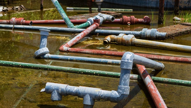 Pipes are scattered haphazardly in swampy water next to chemical tanks at a facility where industrial waste has been stored in Waycross, Ga.