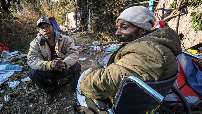 Jeffery Byrd, left, and Roc Peeler, right, hang out at a homeless camp in a fenced area between an interstate offramp and Jefferson Street.November 29, 2017