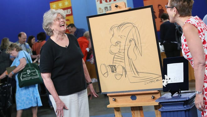 Helen is filmed with a drawing of Linus by Charles Schulz that was appraised by Kathleen Guzman, right, for $10,000 during the Antiques Roadshow summer 2013 tour stop at Cobo Center.