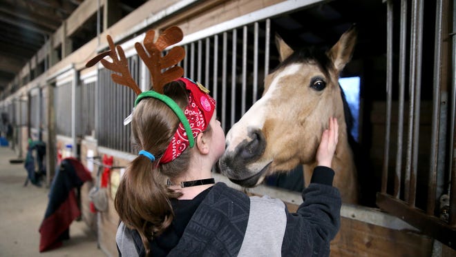 A foster child visits with a horse in a stable at The Riding Place in Port Orchard on Friday. The equestrian center had a holiday party for foster kids.