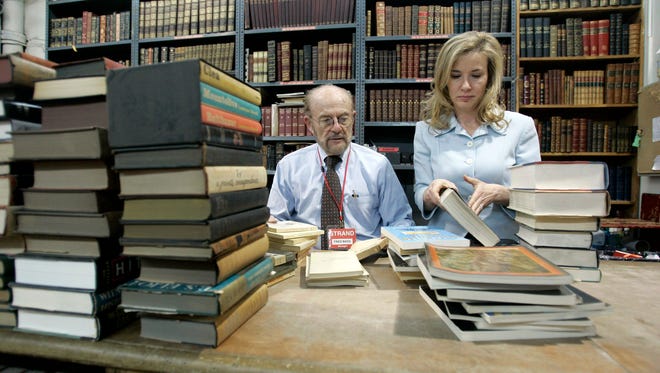 FILE - In this Feb. 21, 2007 file photo,  Fred Bass, left, owner of the Strand bookstore, sorts out a batch of used books with his daughter Nancy Bass Wyden in New York.  Bass, the co-owner of one of the country's largest and most beloved independent bookstores died Wednesday, Jan. 3, 2018, at his home in Manhattan. He was 89.  (AP Photo/Mary Altaffer)