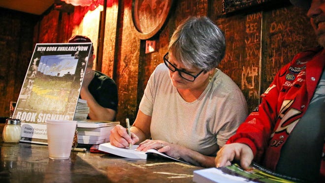 In this Feb. 9, 2018, photo, Lexie Miller Wyman signs copies of her book at Moose's Saloon in Kalispell, Mont. (Greg Lindstrom/Flathead Beacon via AP)