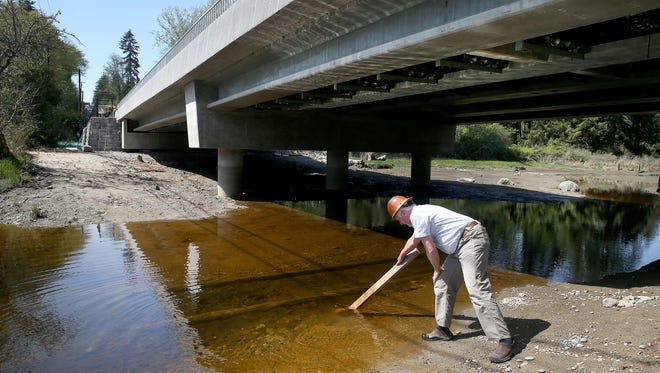 FILE PHOTO – David Berry of Redside Construction uses a board to fish a hammer out of Carpenter Creek at the new West Kingston Road Bridge in April 2018.