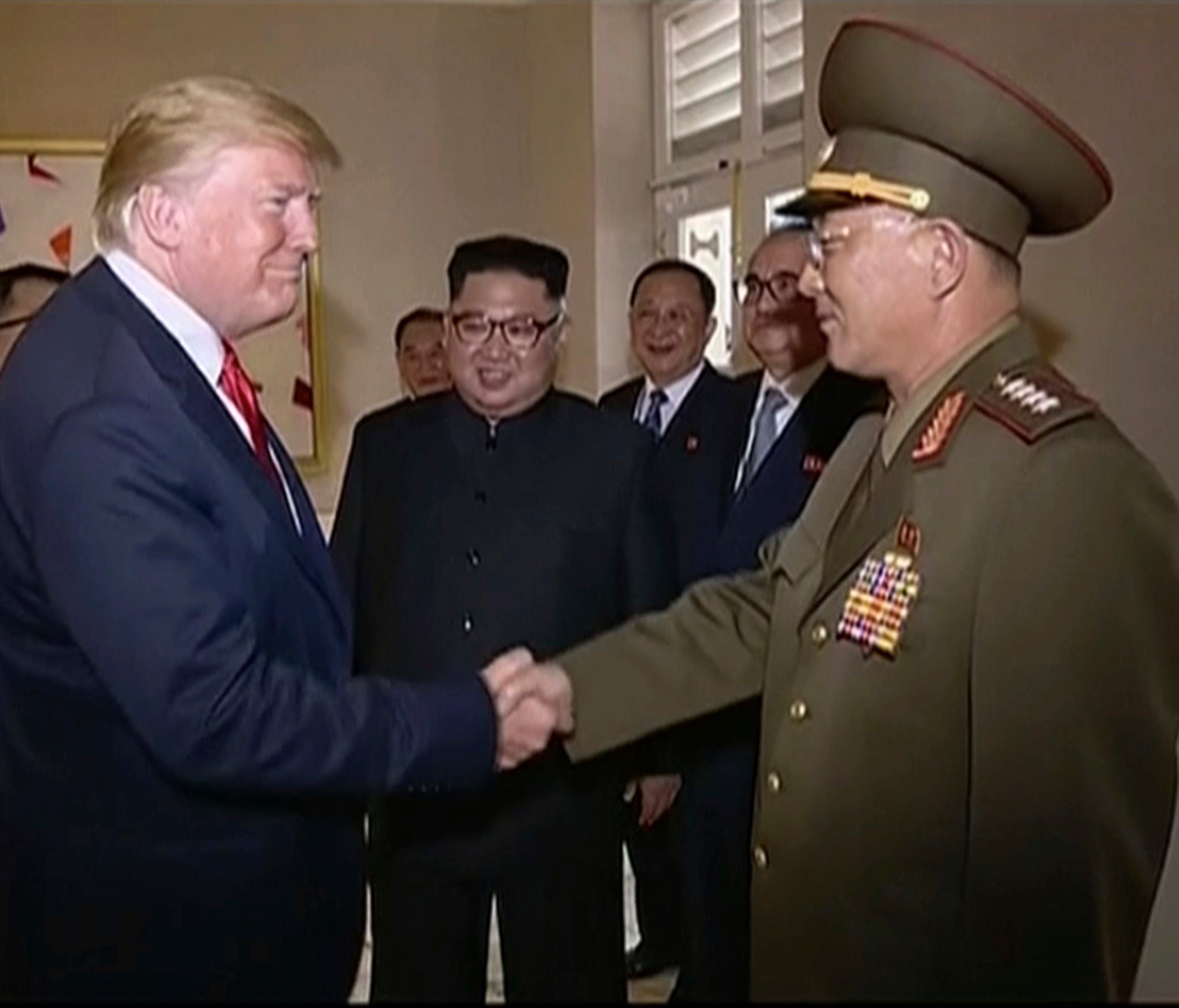 In this image made from June 12, 2018, video released by KRT, President Donald Trump shakes hands with No Kwang Chol, minister of People's Armed Forces of North Korea, as North Korean leader Kim Jong Un, center, introduces Trump to the general during