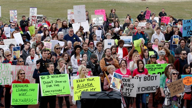 In this Feb. 28, 2012 file photo, people at the state Capitol in Oklahoma City cheer at a rally in opposition to the state Senate's passage of a bill that grants the rights of personhood to fertilized human eggs.