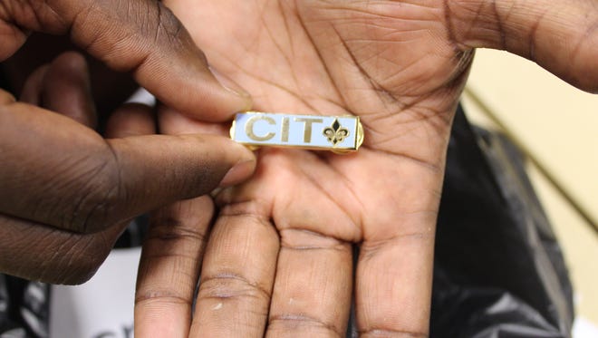 An officer holds his CIT pin after successfully completing the crisis intervention training in late February.