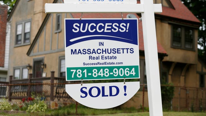 A sign hangs in front of a recently sold home in Quincy, Mass.