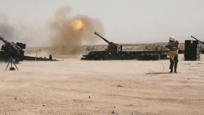 Iraqi security forces backed by Shiite and Sunni pro-government fighters fire artillery shells against Islamic State positions outside Fallujah, Iraq, on July 13, 2015.