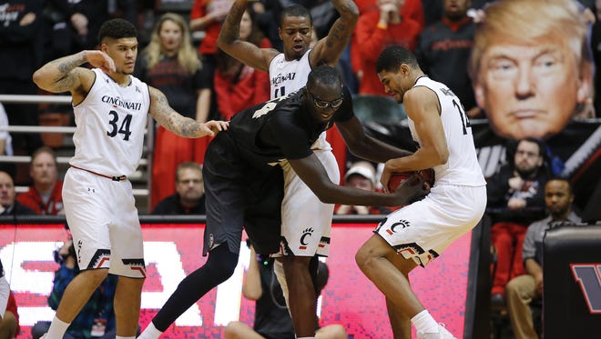 UCF 7-foot-6 center Tacko Fall battles Cincinnati's Kyle Washington for a loose ball during a game last season at UC, with Jarron Cumberland (34) and Gary Clark nearby. UC will face Fall and UCF again Tuesday in Orlando.