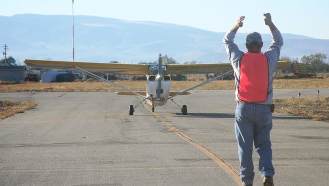 One of the staff at the 2015 Lyon County Fly-In guides a plane to its spot on the apron at the Silver Springs Airport.