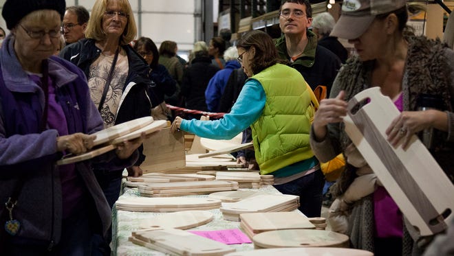 Participants quickly swarm tables full of cutting boards and make their selections as the Bread 'N' Boards fundraising event for the Larimer County Food Bank gets underway at Sears Trostel in Fort Collins Saturday morning.