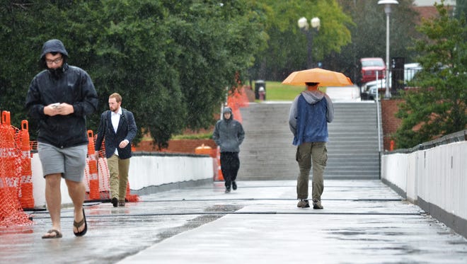 Clemson University students quickly walk across the bridge in front of Cooper Library as rain and wind picked up on Monday, Sept. 11, 2017. Clemson canceled classes Monday and closed most facilities in anticipation of Hurricane Irma's arrival in South Carolina. Classes are expected to resume Tuesday.